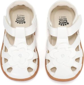White toddler Mary Jane sandals with wide toe box, closed toe, flower detail, and adjustable hook-and-loop strap White toddler Mary Jane sandals with wide toe box, closed toe, flower detail, and adjustable hook-and-loop strap
