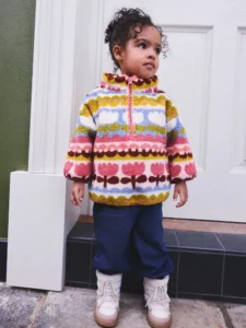 Girl wearing NEXT Pink/Blue Flowers half zip teddy fleece with floral print, chest appliqué, and side pockets