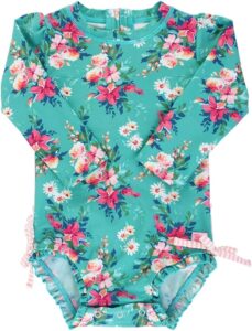 Baby girl wearing a RuffleButts Fancy Me Floral long sleeve one-piece rash guard swimsuit with UPF 50+ sun protection, floral print, and signature rear ruffles Baby girl wearing a RuffleButts Fancy Me Floral long sleeve one-piece rash guard swimsuit with UPF 50+ sun protection, floral print, and signature rear ruffles